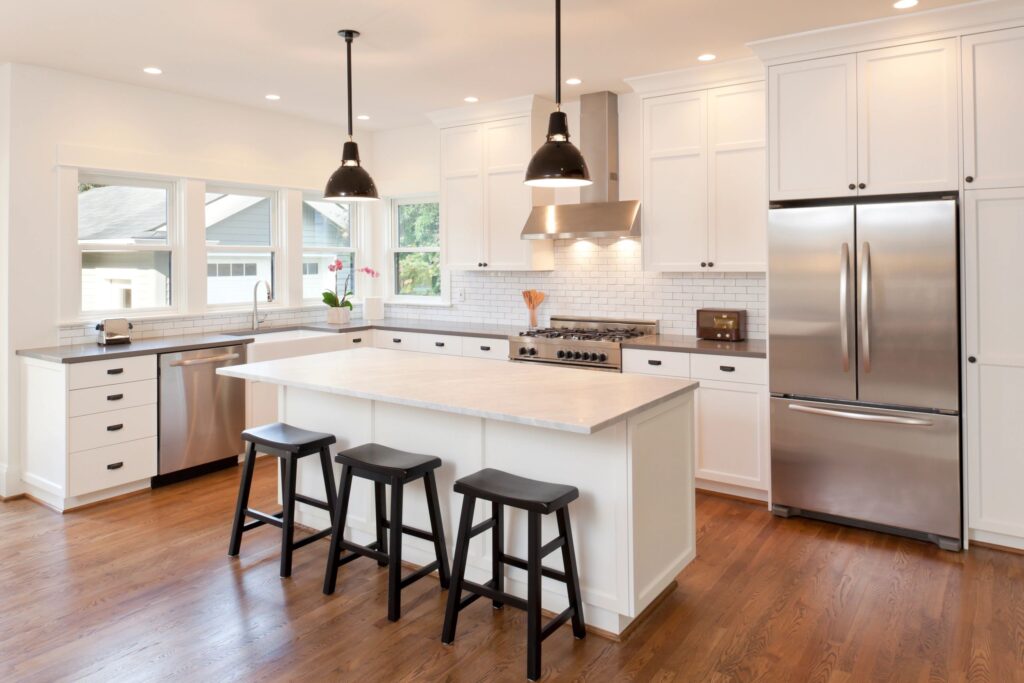 Modern indoor kitchen with white custom cabinets, quartz countertops, and stainless steel appliances. Designed and built