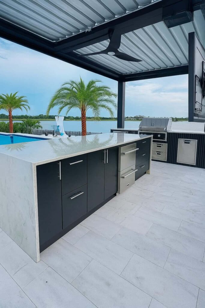 Outdoor kitchen with black PVC and StarBoard waterproof cabinets, quartz countertop, and Blazer stainless steel appliances. Designed and built by Evolux Cabinets for luxury outdoor living.
