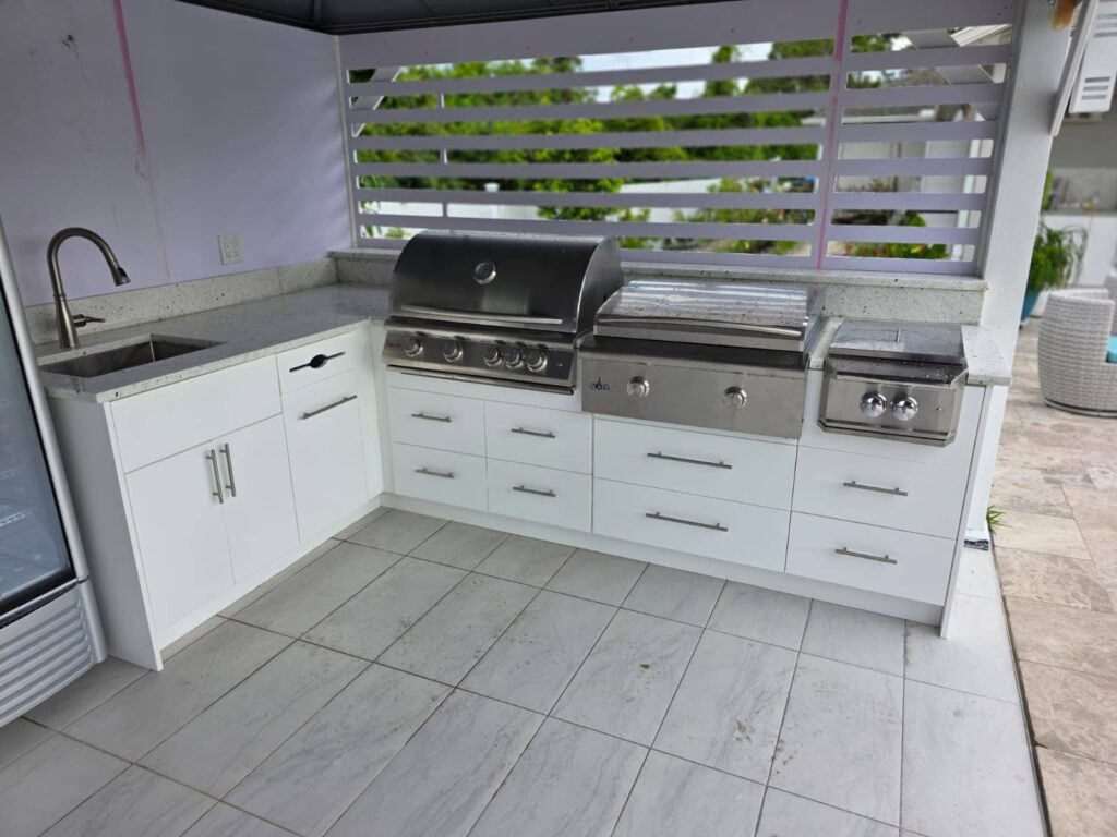 Modern outdoor kitchen with white waterproof cabinets, quartz countertop, and stainless steel grill. Designed and built by Evolux Cabinets for elegant outdoor living.