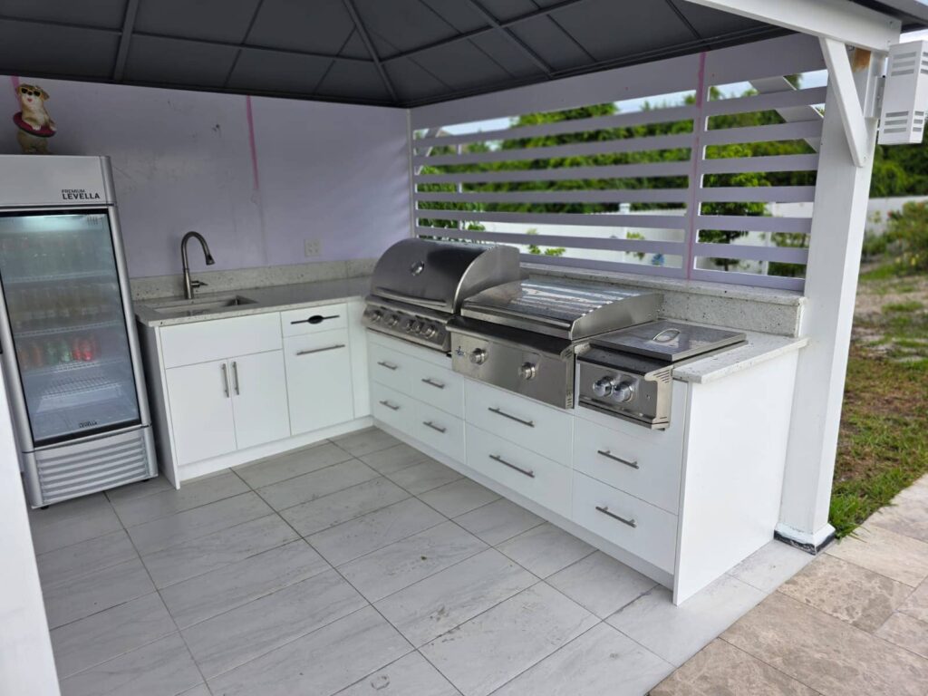 Modern outdoor kitchen with white waterproof cabinets, quartz countertop, and stainless steel grill. Designed and built by Evolux Cabinets for elegant outdoor living.