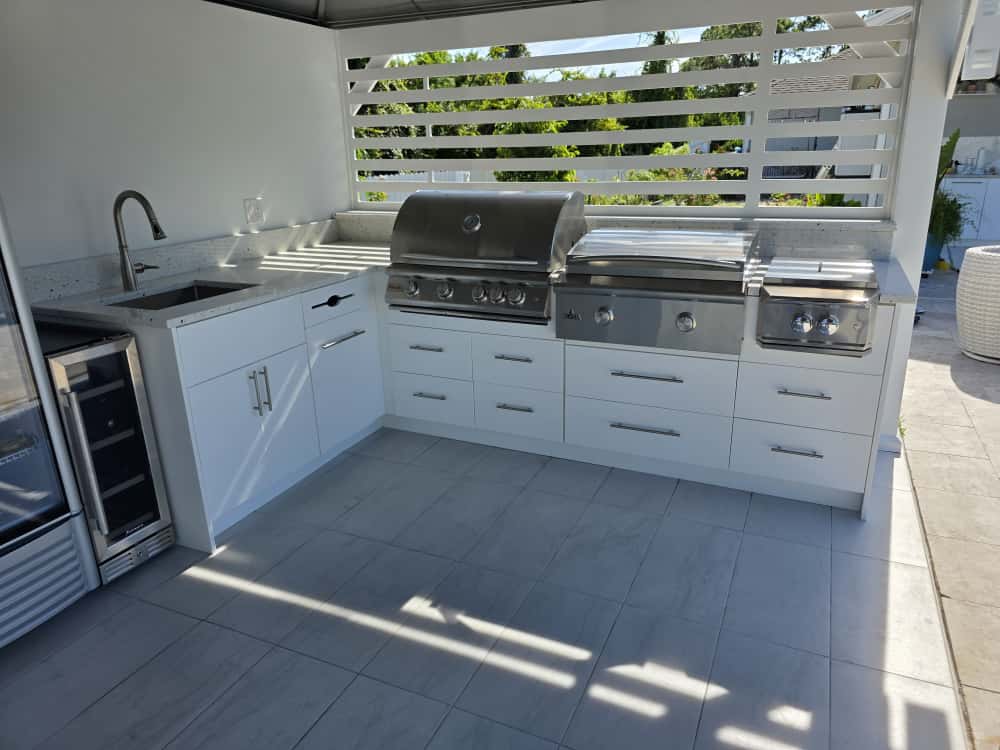 Modern outdoor kitchen with white waterproof cabinets, quartz countertop, and stainless steel grill. Designed and built by Evolux Cabinets for elegant outdoor living.