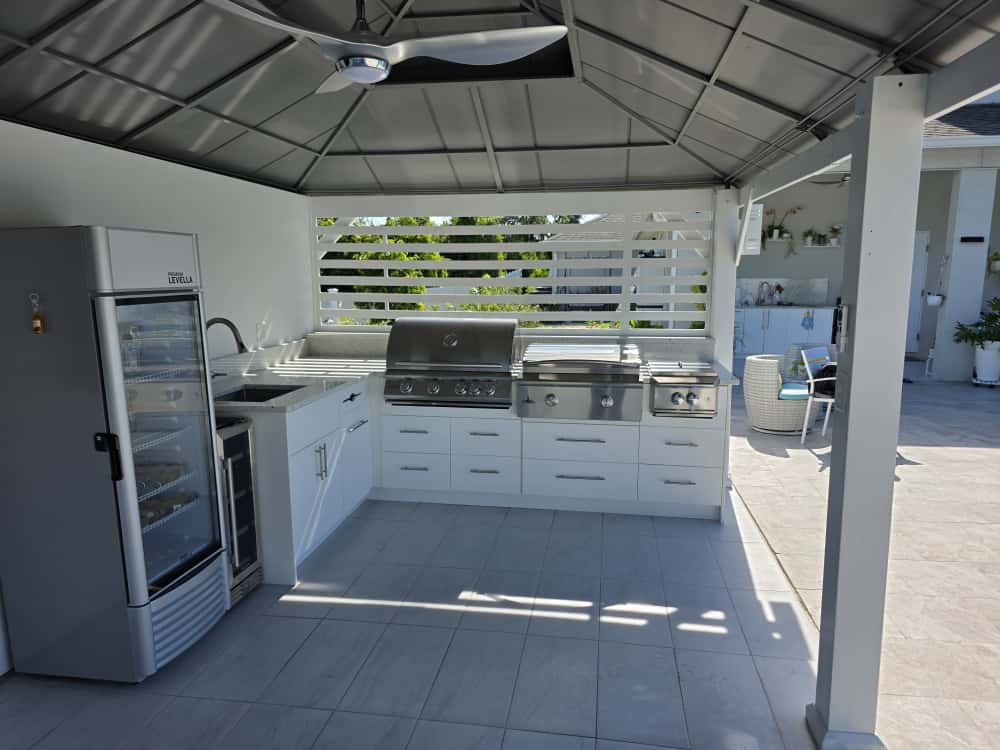 Modern outdoor kitchen with white waterproof cabinets, quartz countertop, and stainless steel grill. Designed and built by Evolux Cabinets for elegant outdoor living.