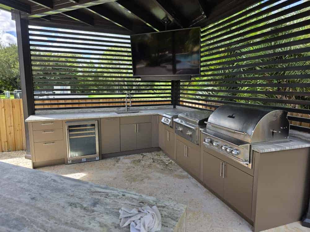 Outdoor kitchen with taupe PVC and StarBoard waterproof cabinets, quartz countertop, and Blazer stainless steel appliances. Designed and built by Evolux Cabinets for luxury outdoor living.