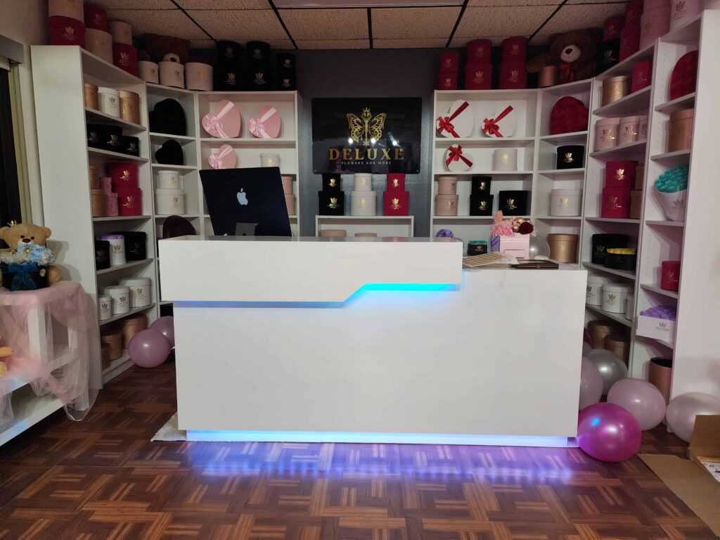 Custom reception desk and display shelves built by Evolux Cabinets for a flower shop. Modern design with LED lighting and organized shelving for product display.