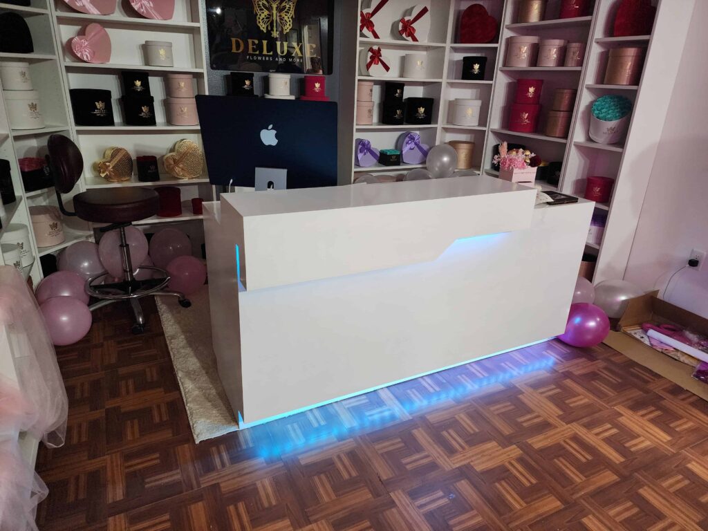 Custom reception desk and display shelves built by Evolux Cabinets for a flower shop. Modern design with LED lighting and organized shelving for product display.