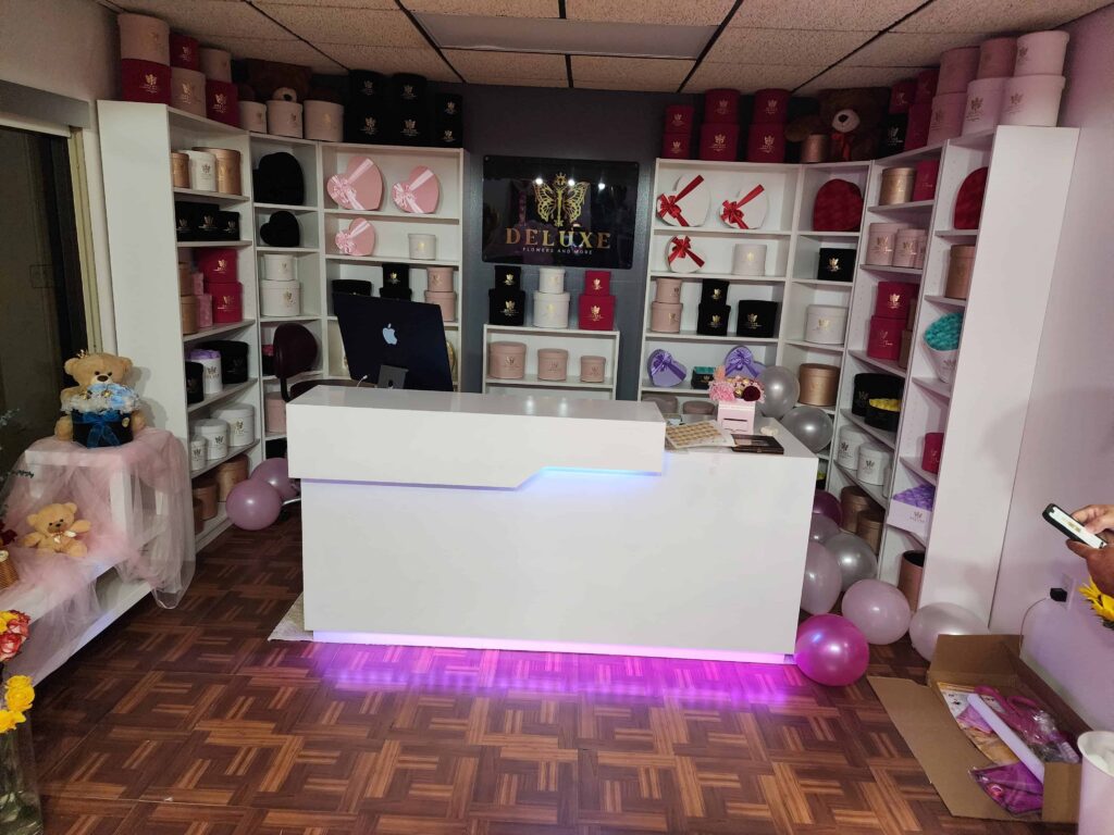 Custom reception desk and display shelves built by Evolux Cabinets for a flower shop. Modern design with LED lighting and organized shelving for product display.