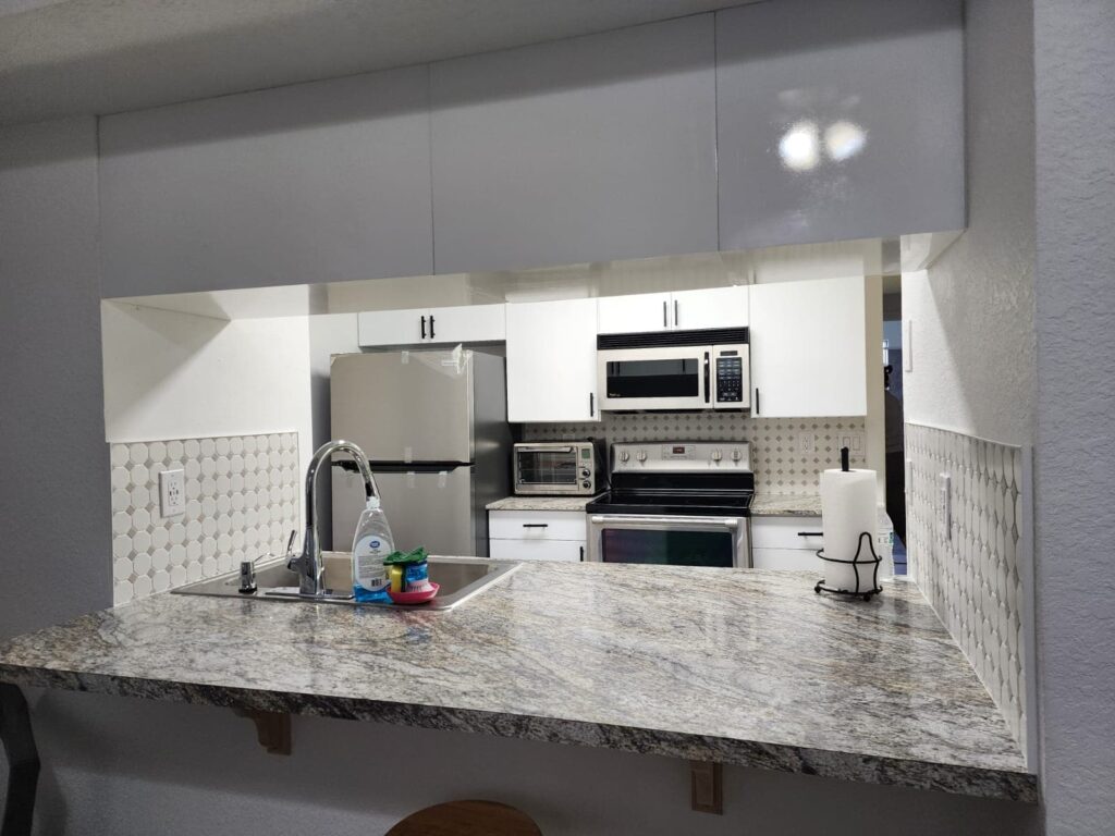 Compact modern kitchen with waterproof PVC cabinets and granite countertops by Evolux Cabinets.