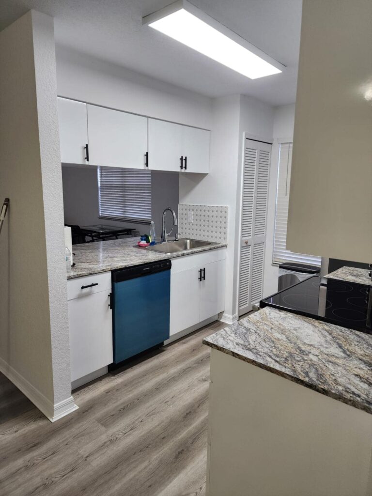 Compact modern kitchen with waterproof PVC cabinets and granite countertops by Evolux Cabinets.