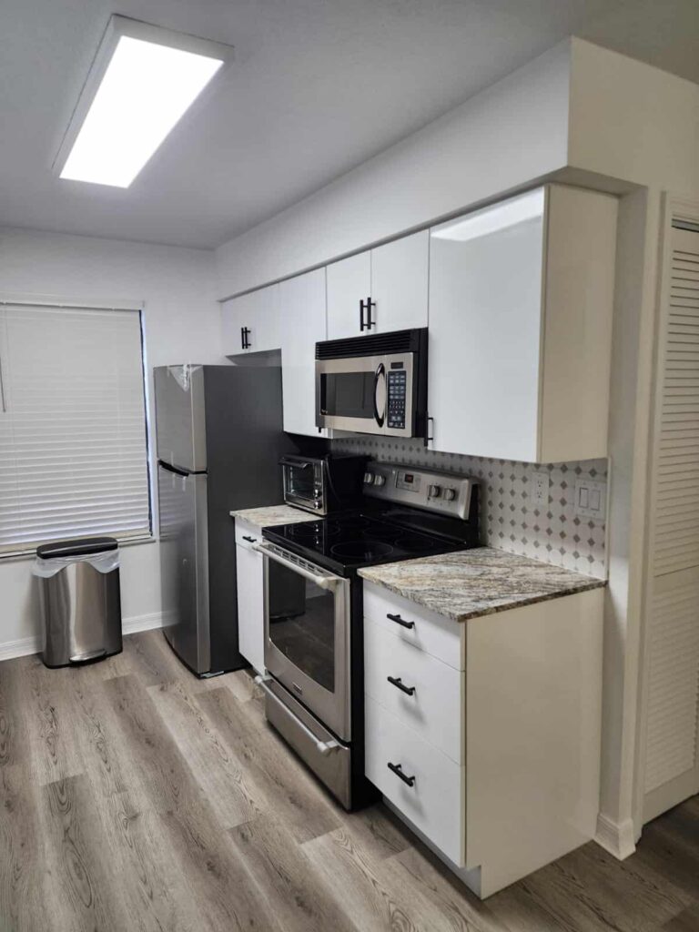 Compact modern kitchen with waterproof PVC cabinets and granite countertops by Evolux Cabinets.