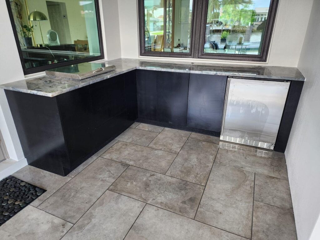 Outdoor kitchen with black PVC and StarBoard waterproof cabinets, quartz countertop, and Blazer stainless steel grill. Designed and built by Evolux Cabinets for luxury outdoor living.