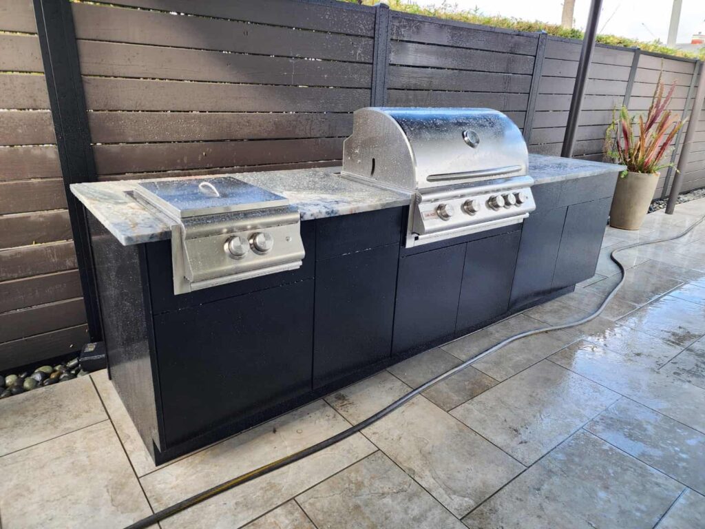 Outdoor kitchen with black PVC and StarBoard waterproof cabinets, quartz countertop, and Blazer stainless steel grill. Designed and built by Evolux Cabinets for luxury outdoor living.