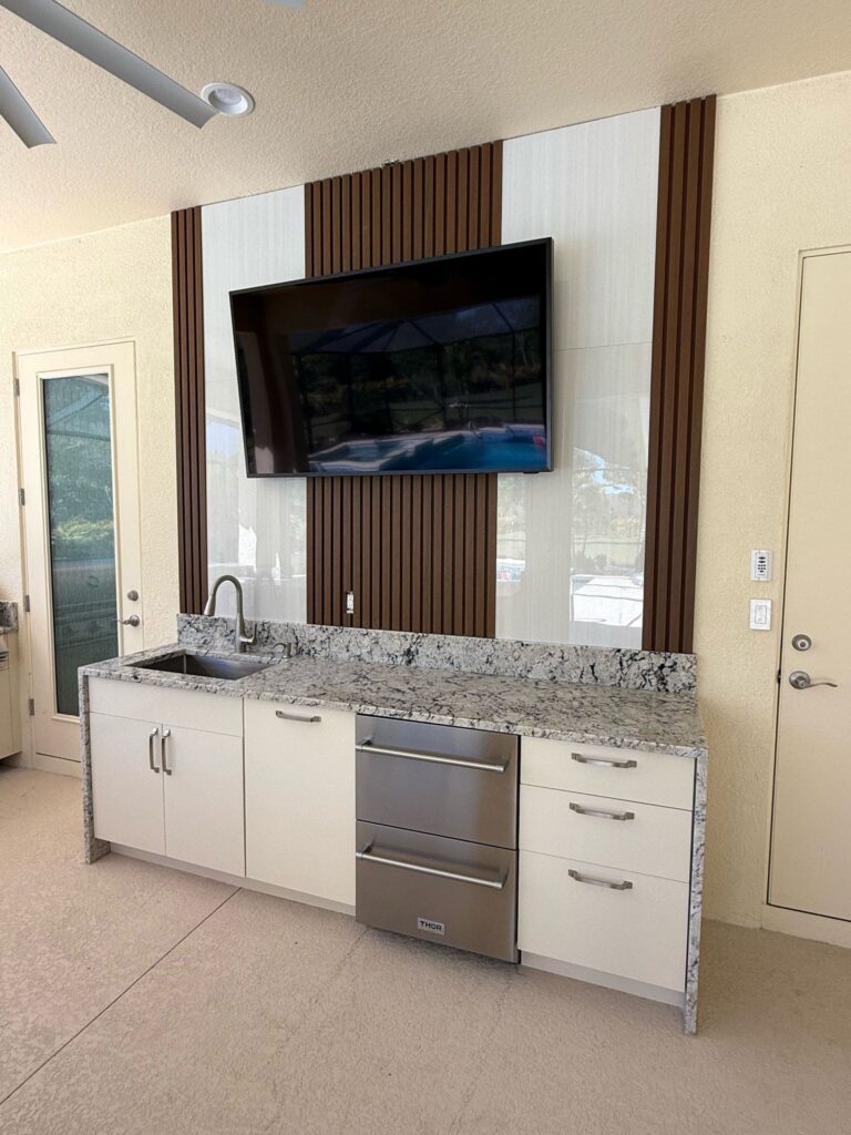 Outdoor kitchen with light beige waterproof cabinets, quartz countertops, and Blazer stainless steel appliances. Designed and built by Evolux Cabinets for elegant outdoor living.