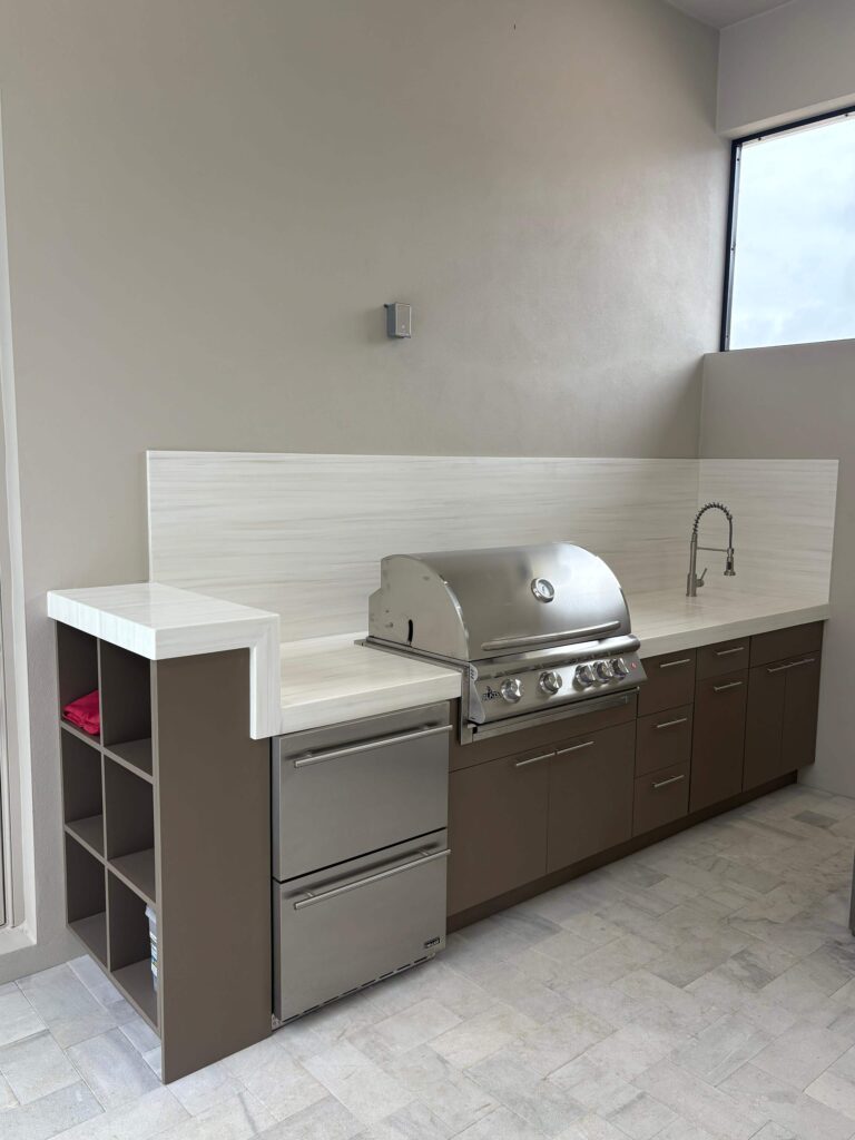 Modern outdoor kitchen with brown waterproof cabinets, Durasing countertop, and stainless steel grill. Built by Evolux Cabinets for stylish and durable outdoor living.