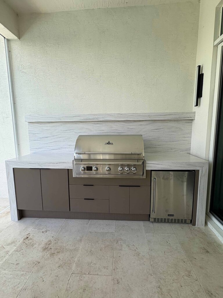 Modern outdoor kitchen with brown waterproof cabinets, Durasing countertop, and stainless steel grill. Built by Evolux Cabinets for stylish and durable outdoor living.