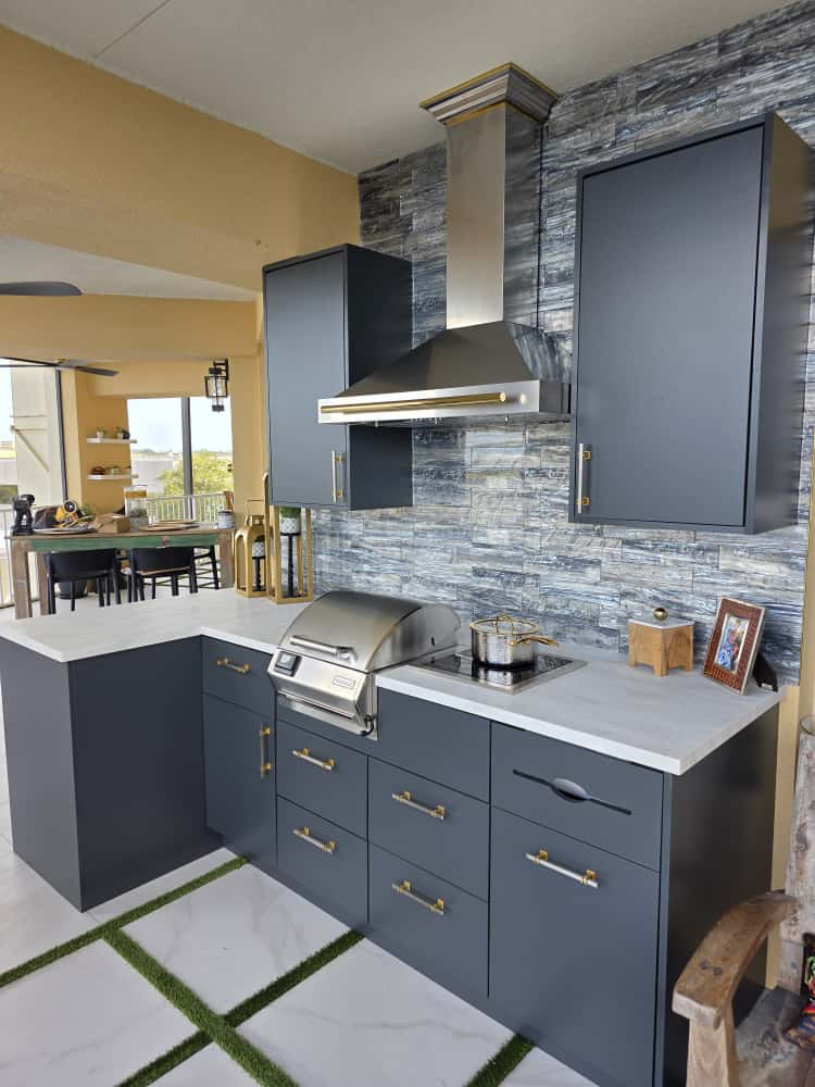 Modern outdoor kitchen with waterproof gray cabinets, Durasing countertop, and stainless steel range hood. Weather-resistant outdoor cabinetry by Evolux Cabinets.